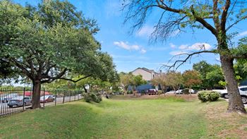 a grassy area with trees and a building in the background