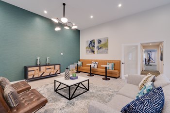 Clubhouse with light tan couch, small tables, blue accent wall, and multiple seating areas. - Photo Gallery 26