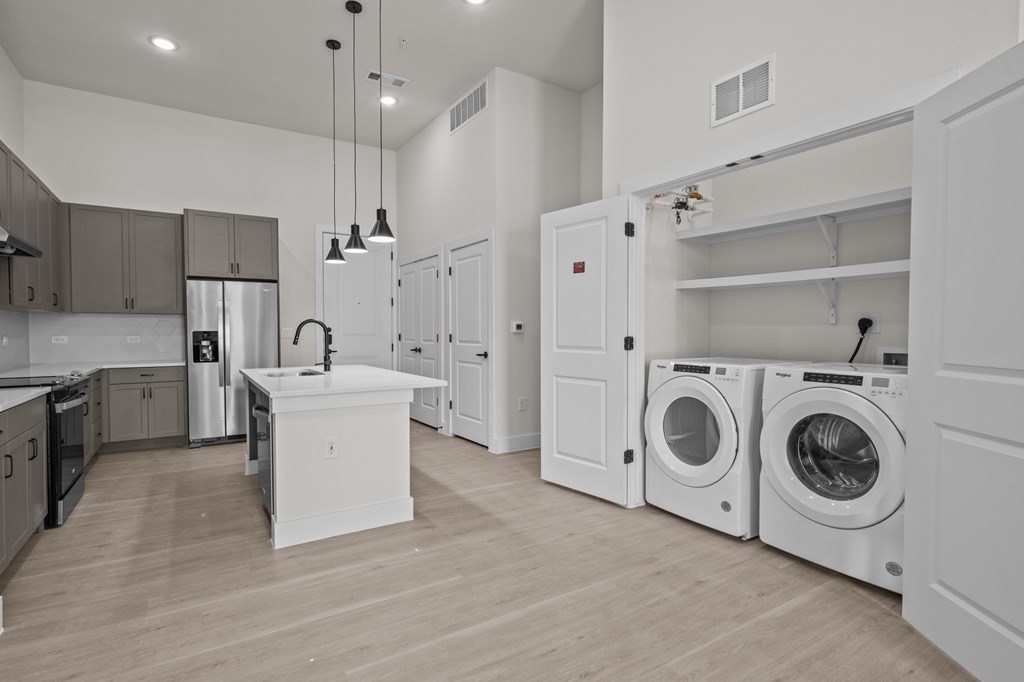 A modern kitchen with a white island and a washer and dryer in the laundry room.