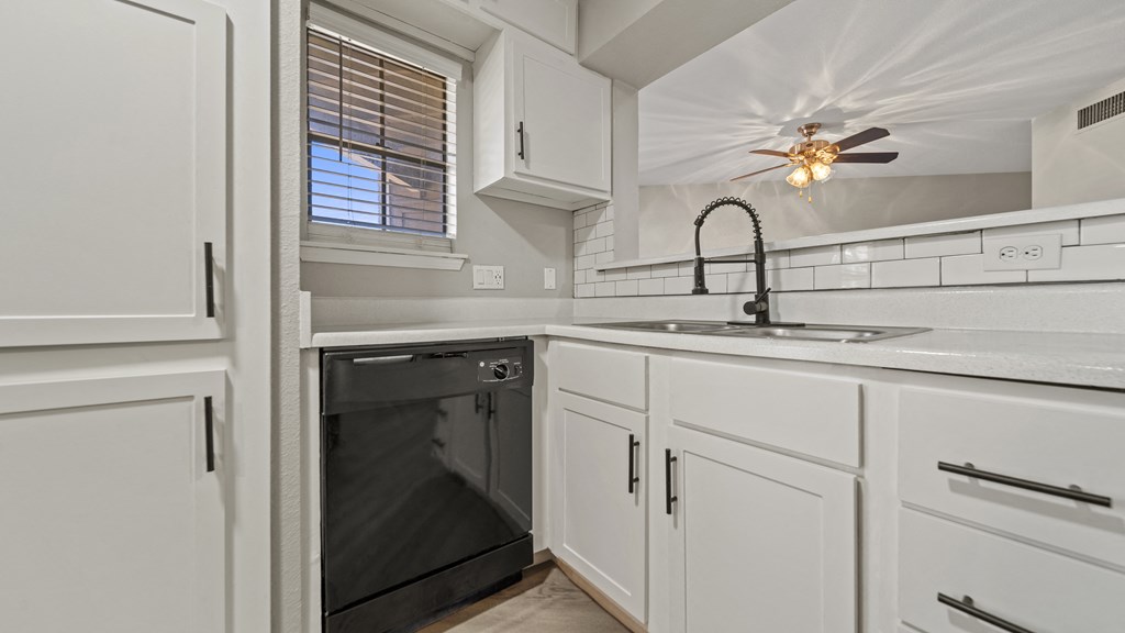 a kitchen with white cabinets and a black dishwasher