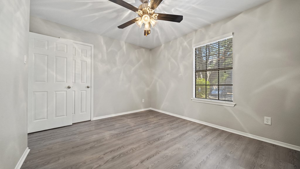 a bedroom with hardwood floors and a ceiling fan