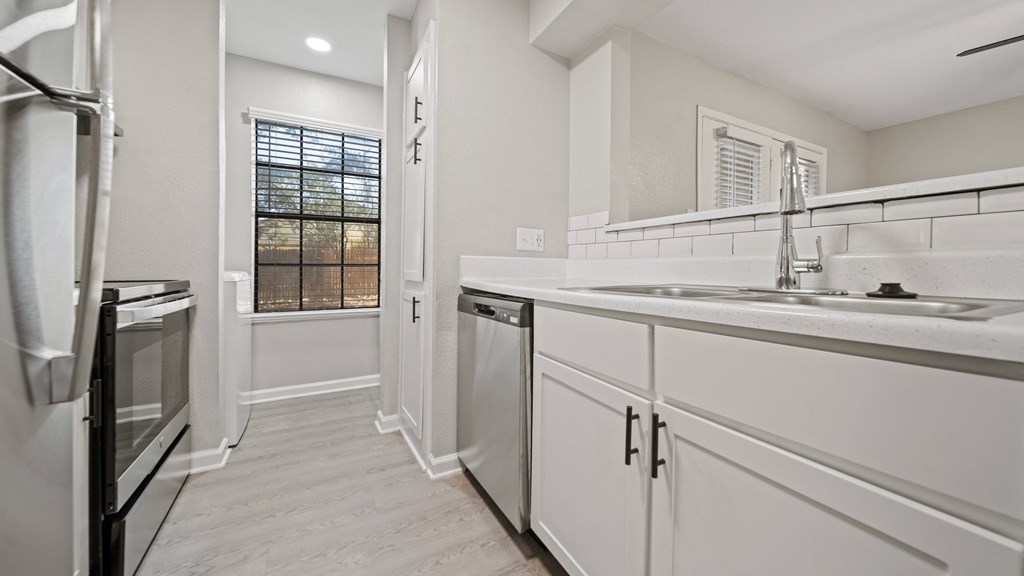 a kitchen with white cabinets and a window