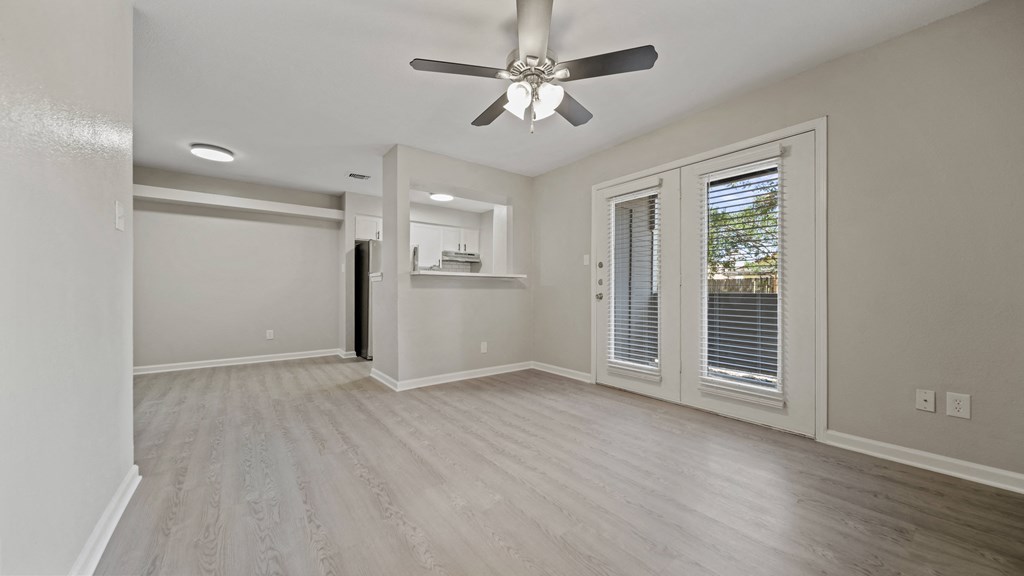 an empty living room with a ceiling fan