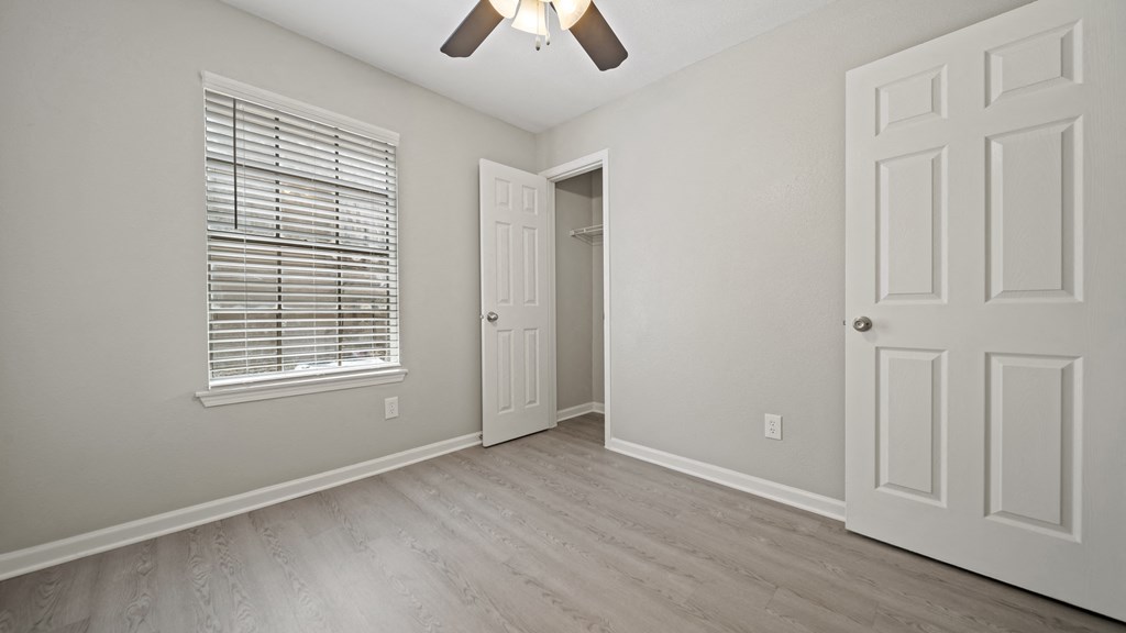 a bedroom with hardwood floors and a ceiling fan