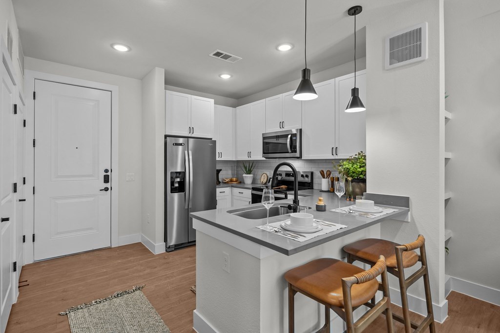 A kitchen with a white counter and brown chairs.