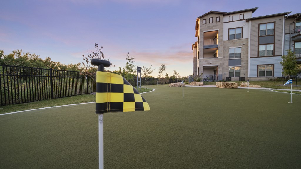 a yellow and black checkered flag on a baseball field in front of an apartment building