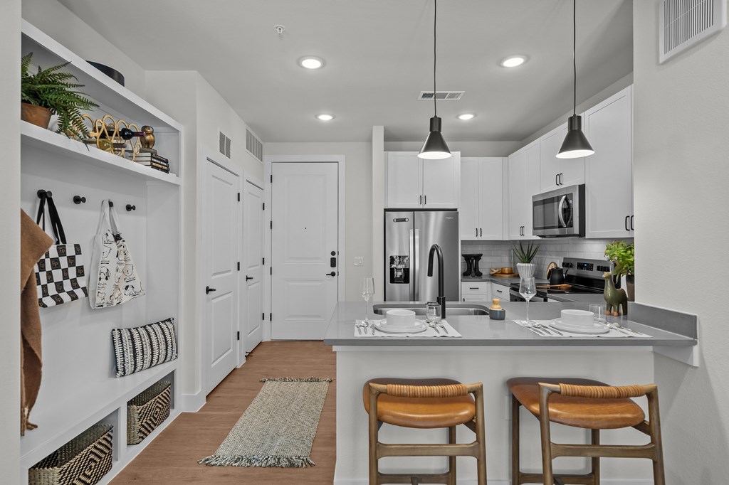 A modern kitchen with white cabinets and a checkered towel hanging on the wall.