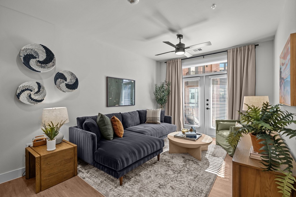 A living room with a grey couch, a coffee table, and a ceiling fan.