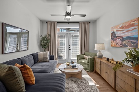 A living room with a grey sofa, a coffee table, a ceiling fan, and a painting on the wall.