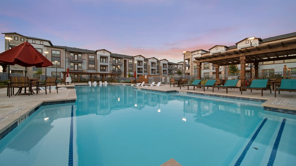 a swimming pool with lounge chairs and umbrellas in front of a building