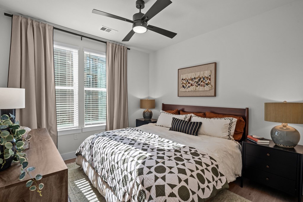 A bedroom with a bed, nightstand, and a ceiling fan.