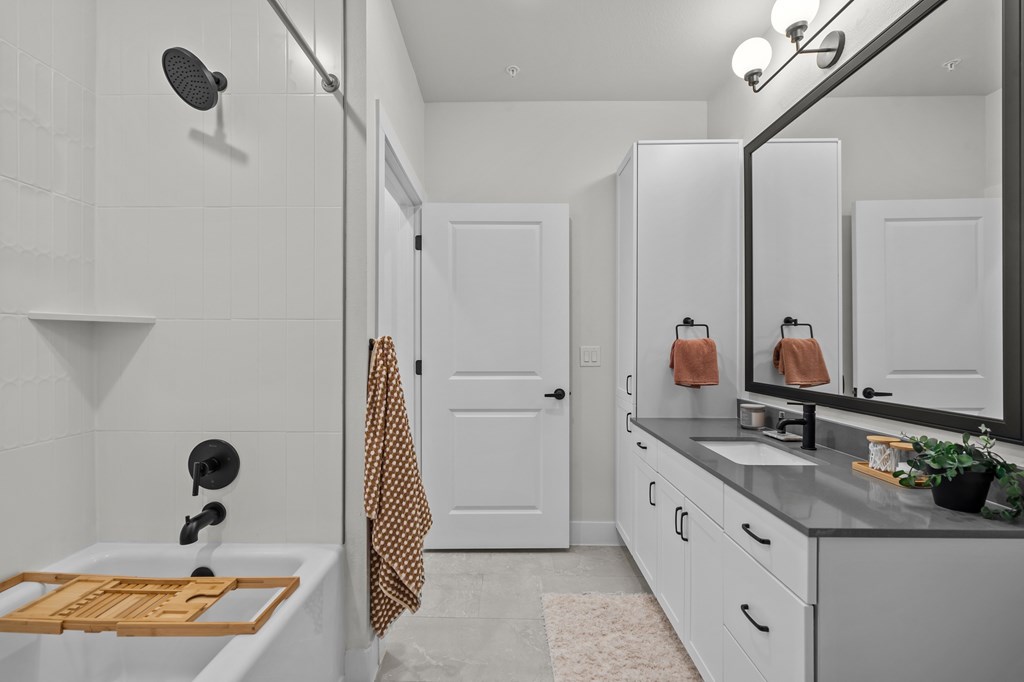 A bathroom with a white tub and a wooden mat.
