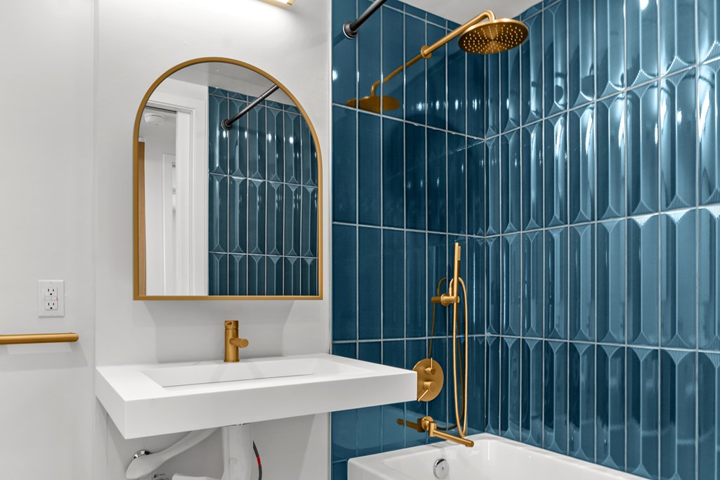 A white sink is under a mirror in a blue tiled bathroom.