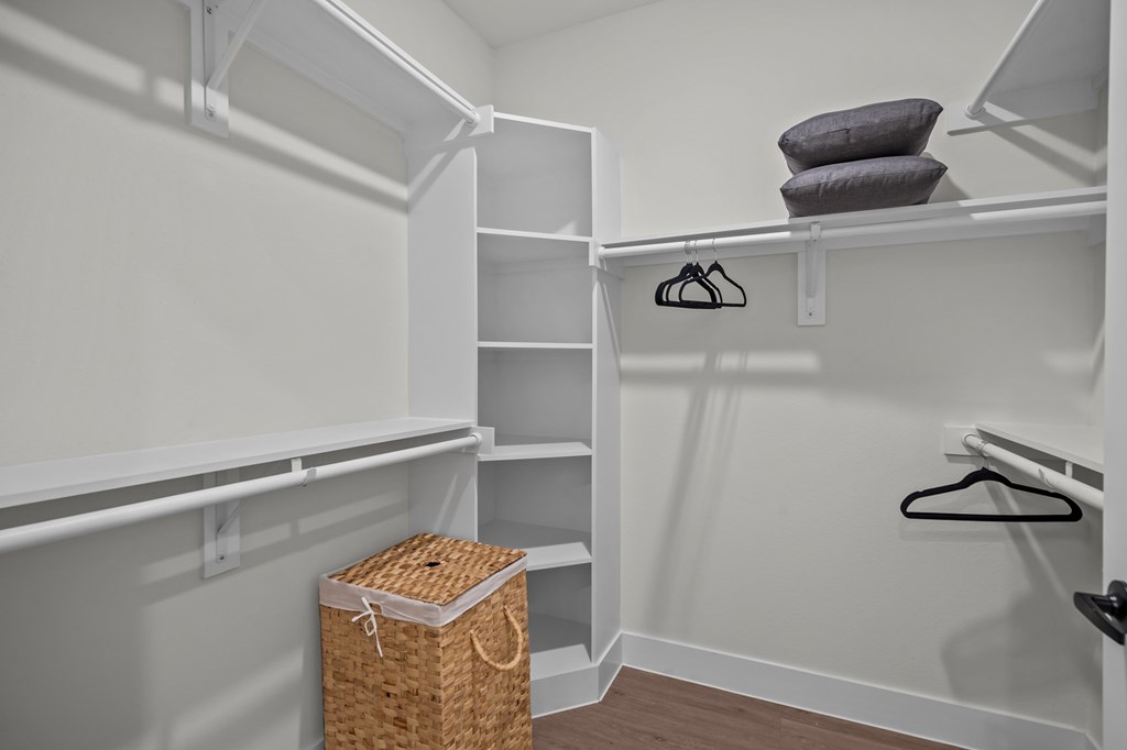 A white closet with a basket and a hanger.