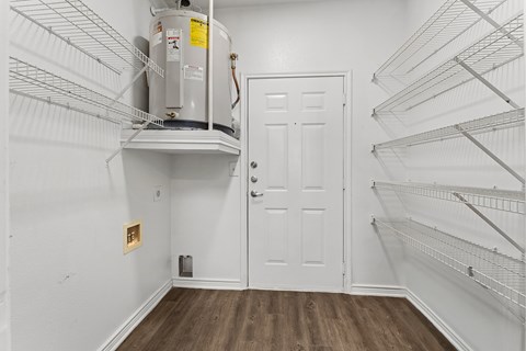 A white door is in a room with a wood floor and a wall with a small hole in it.