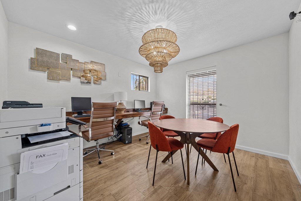 an office with a table and chairs and a desk with a computer and a printer