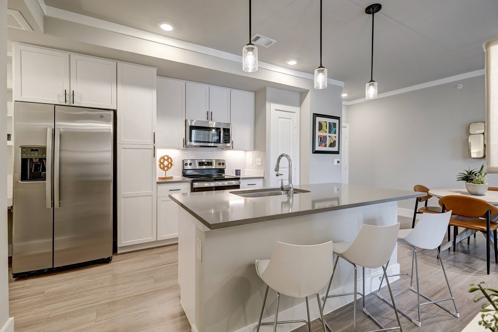a kitchen with a large island and a stainless steel refrigerator