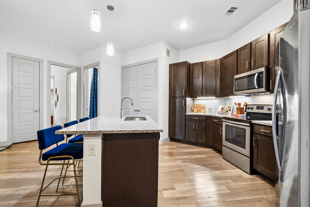 A kitchen with a white island and blue chairs.