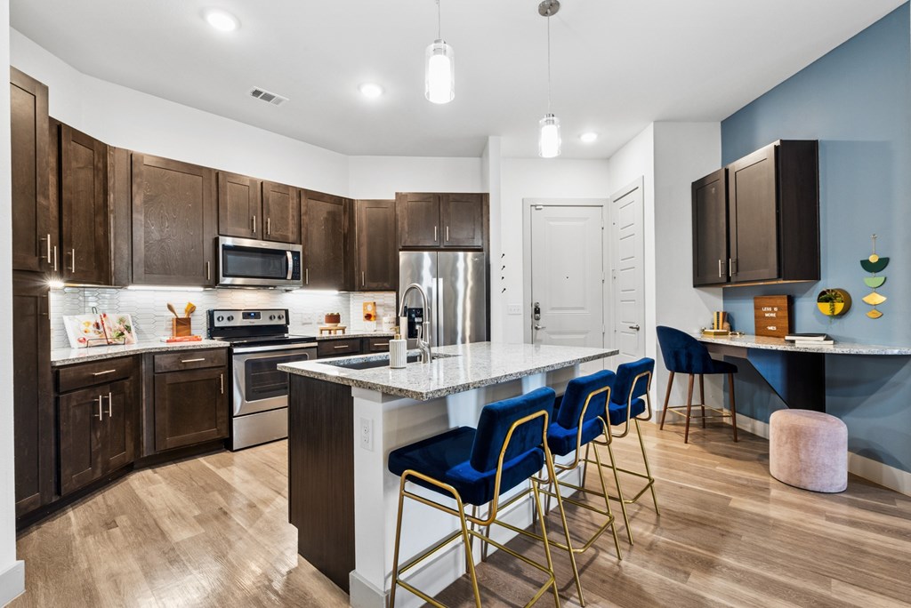 A kitchen with a white island and blue chairs.