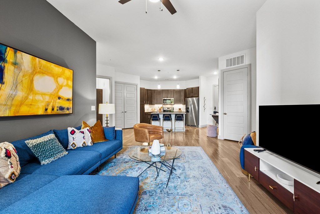 A living room with a blue couch and a painting on the wall.