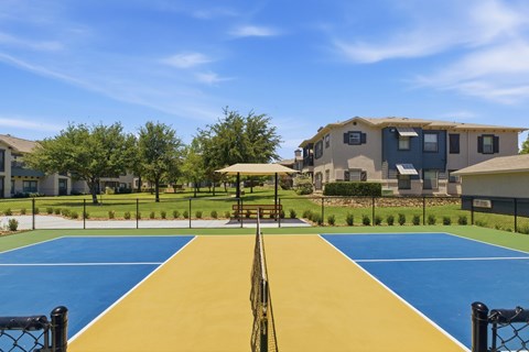A playground with a blue and yellow surface and a black fence.