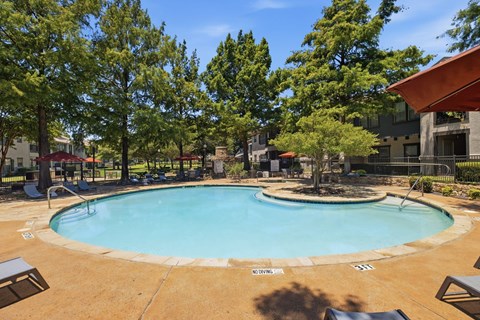 A small pool surrounded by trees and a building.