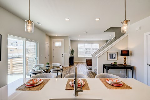 A modern dining room with a long table set for a meal.