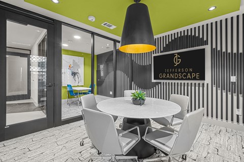 A modern dining area with a white table and chairs, a black pendant light, and a sign that reads