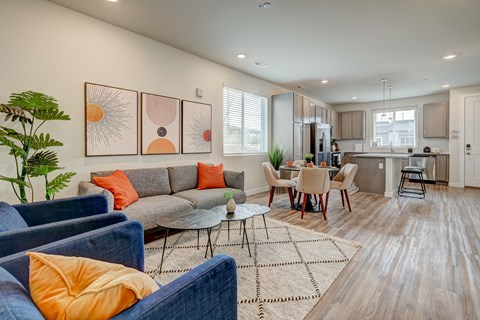 A living room with a grey couch and orange pillows.