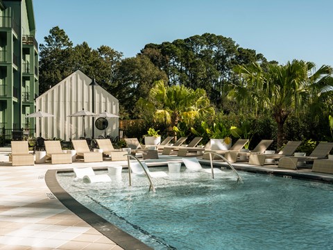A pool with a waterfall and lounge chairs.