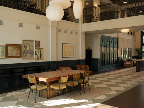 A large dining room with a checkered floor and a long table with chairs.