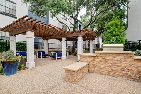 a patio with a stone wall and a pergola