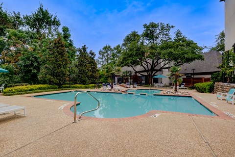 a swimming pool with trees and a building in the background