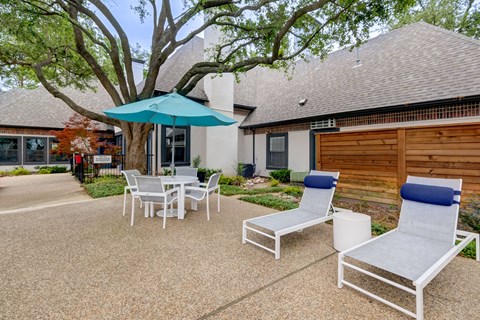 a patio with chairs and an umbrella in front of a house