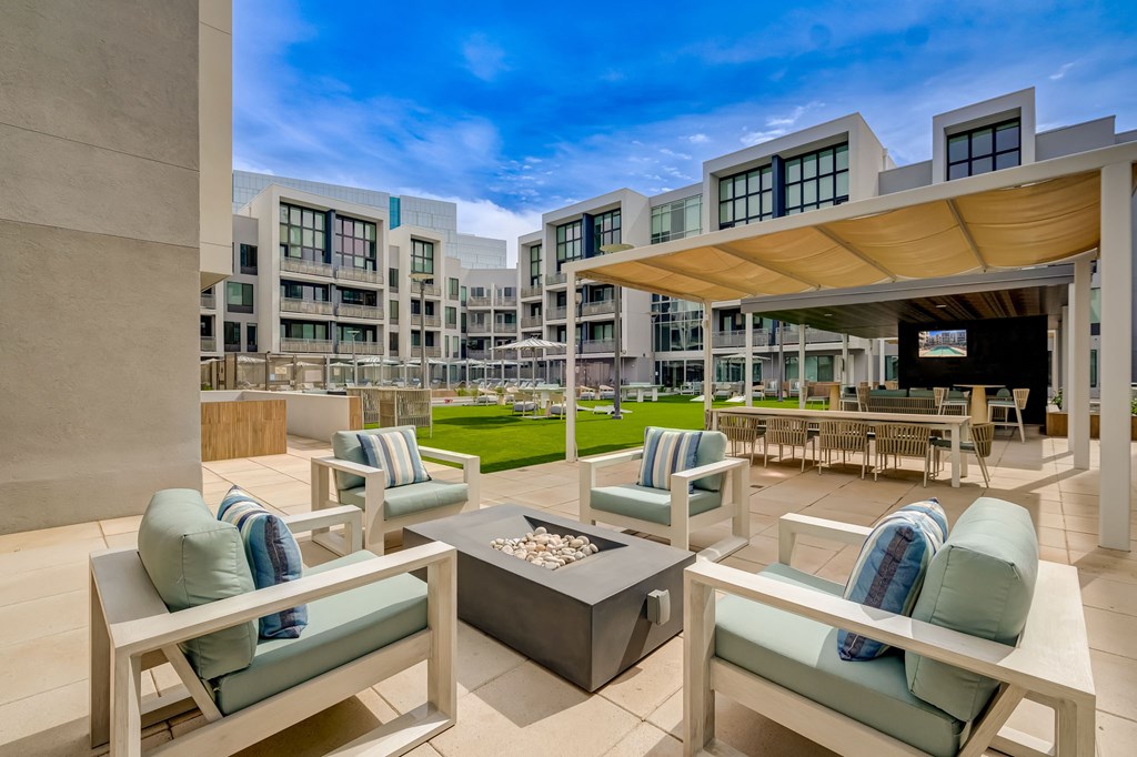 A modern outdoor seating area with blue cushions and a fire pit.