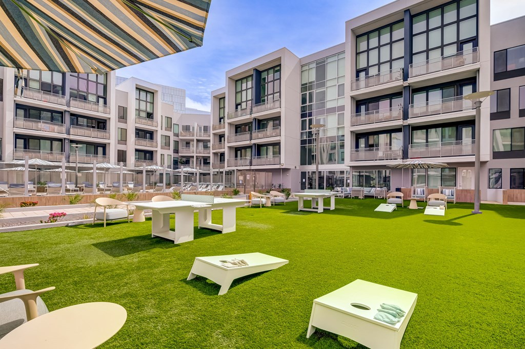 A modern building with a grassy courtyard and tables and chairs.