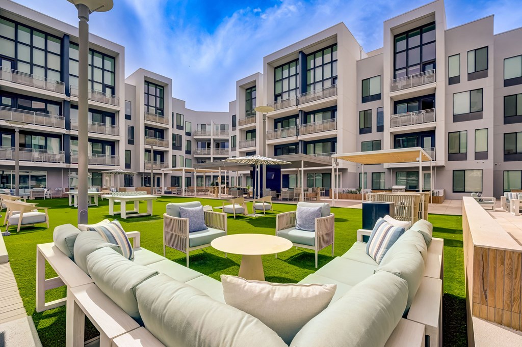 A modern outdoor seating area with white cushioned benches and tables.