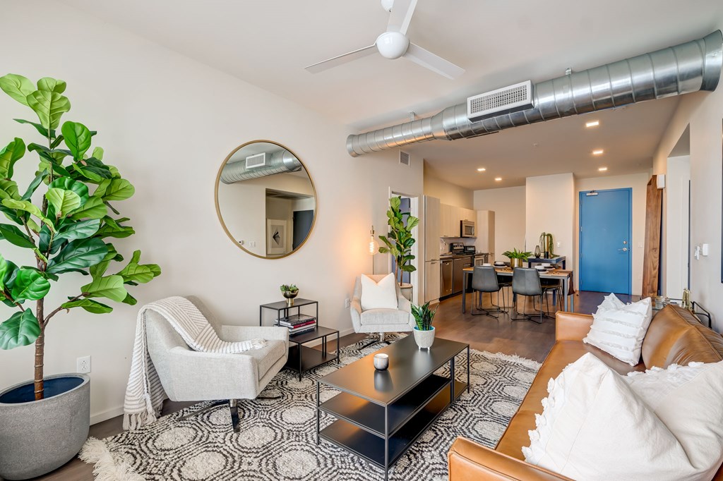 A living room with a white couch, a coffee table, and a potted plant.