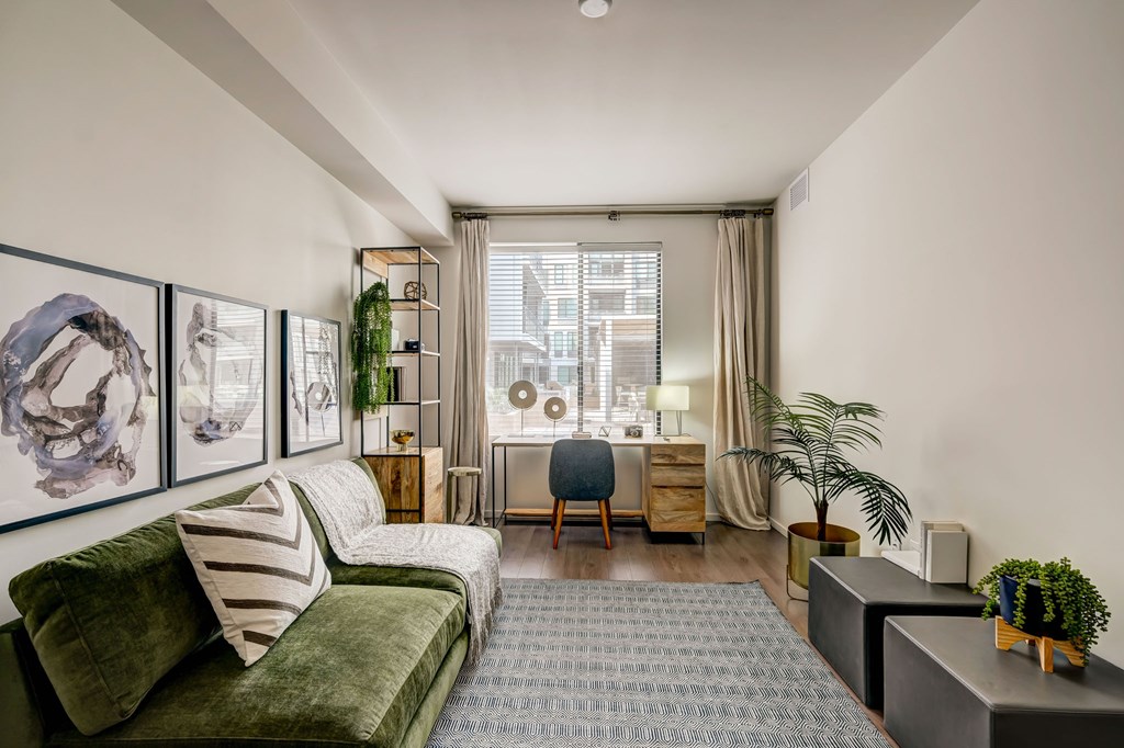 A living room with a green couch and a grey rug.