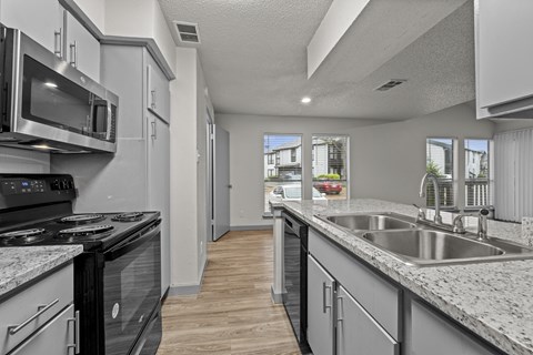 A kitchen with a black stove top oven and a white microwave.