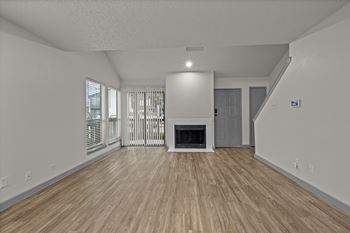 A spacious living room with a fireplace and wooden flooring.