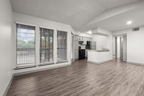 A spacious room with wooden flooring and a kitchen area.