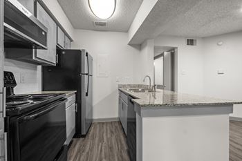 A kitchen with black appliances and a white counter.
