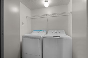 Two white front loading washing machines in a laundry room.