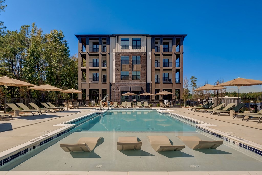 a swimming pool with chairs and a building in the background