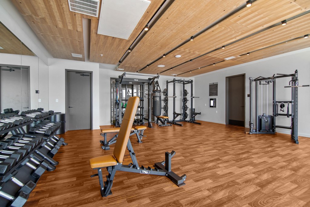 a gym with weights and cardio equipment on a wood floor