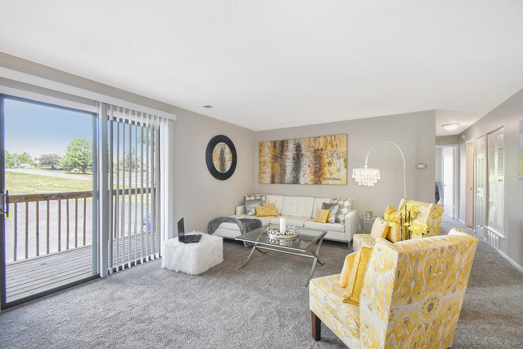 a living room with yellow furniture and a sliding glass door to a balcony