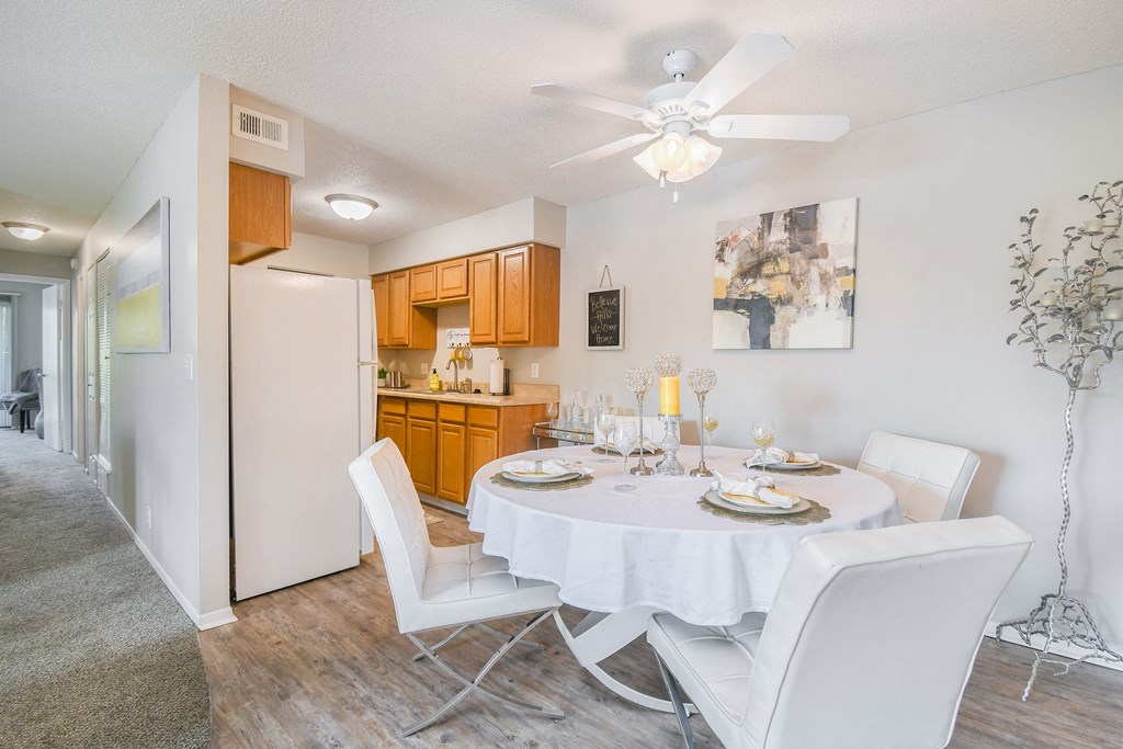 a dining room with a table and chairs and a kitchen with a refrigerator