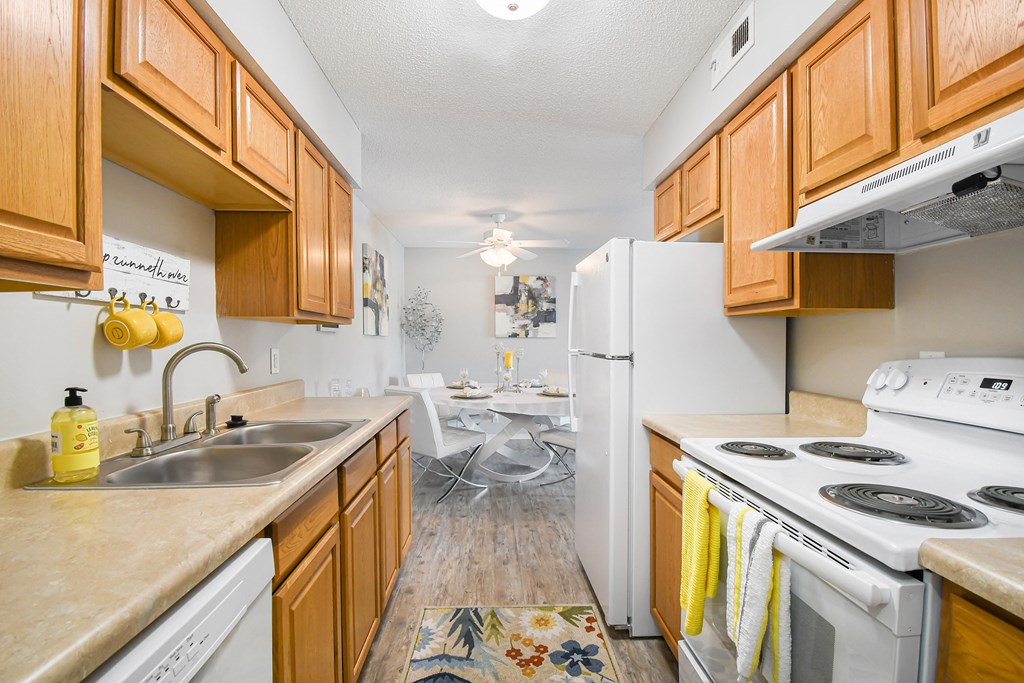 a kitchen with white appliances and wood cabinets     and a dining room