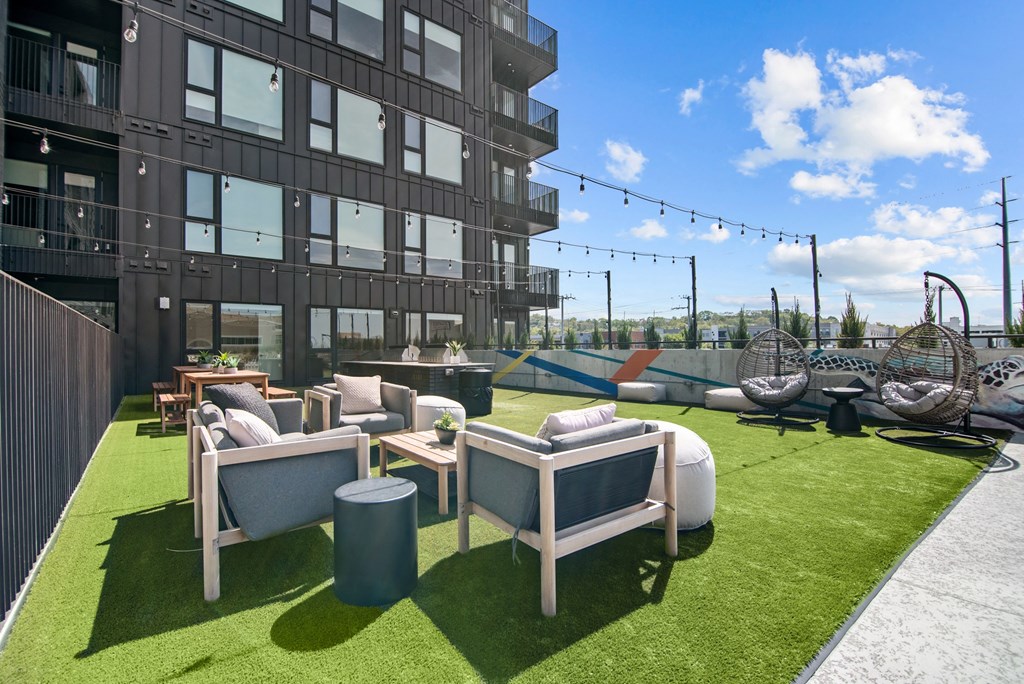 a patio with couches and chairs on a lawn in front of a building